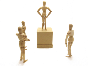 3 wooden stick men surrounding and looking up to a stick man on a pedestal representing authority.
