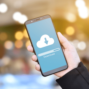 A hand holding a mobile phone with the screen showing a checklist or cheatsheet being downloaded from the cloud.