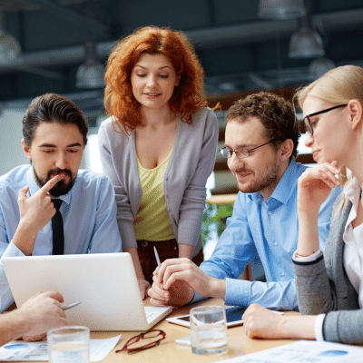 Group of agents gathered around a laptop discussing the latest post for their content goldmine.