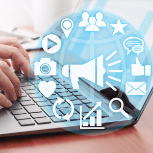Somebody typing on a laptop behind an overlay of a wheel of social icons around a megaphone.