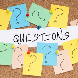 The word "Questions" on a cork board surrounded by several notes pinned all with a large question mark.