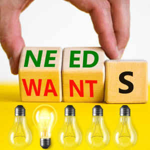 Needs vs Wants in two sides of a cube with four unlit lightbulbs underneath  pointing down and one bulb lit facing up.