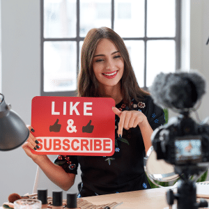 An influential businesswoman with website authority on camera holding up a like and subscribe sign to her audience.
