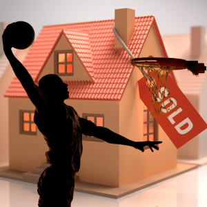 Basketball player slam dunking in front of a house with a sold label.