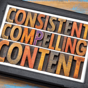 A 3d wooden craft sign on a desk that says "consistent compelling content".