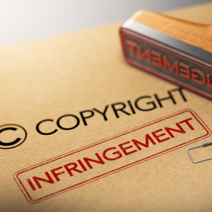 The word Copyright on a folder with 'Infringement' stamped in red underneath and the rubber stamp lying on it's side above.