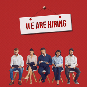 We are hiring sign on a red background.
5 candidates are sitting and filling out applications below.