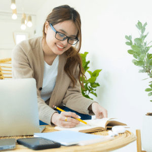Young lady at a desk with a notepad while learning online from her laptop.