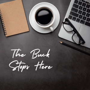 A clean desk with a laptop, cup of coffee and a notepad. A message on the desk says "The buck stops here".